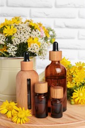Photo of Bottles of essential oil and different wildflowers on wooden board