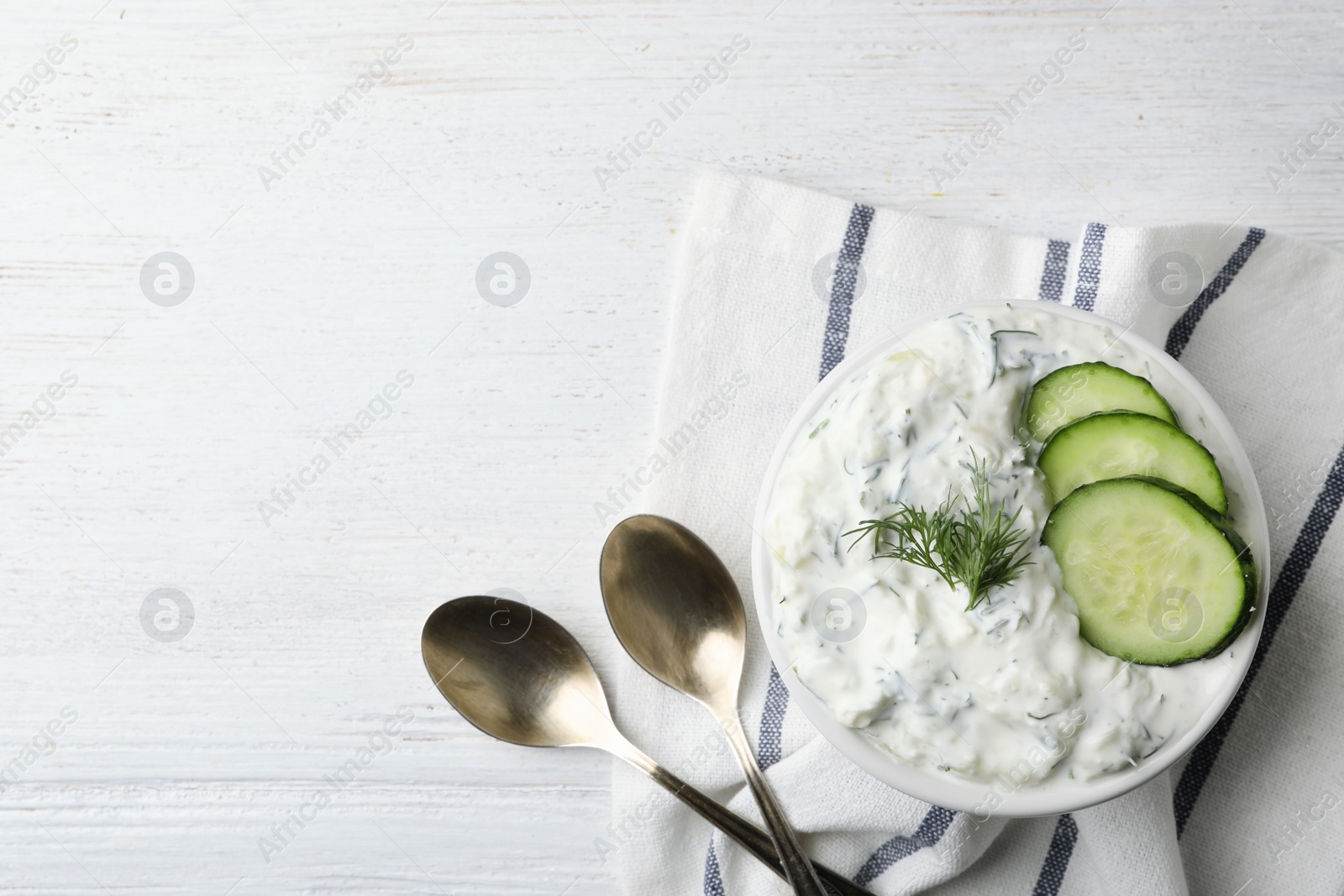 Photo of Cucumber sauce, spoons and space for text on wooden background, flat lay. Traditional Tzatziki