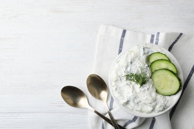 Photo of Cucumber sauce, spoons and space for text on wooden background, flat lay. Traditional Tzatziki