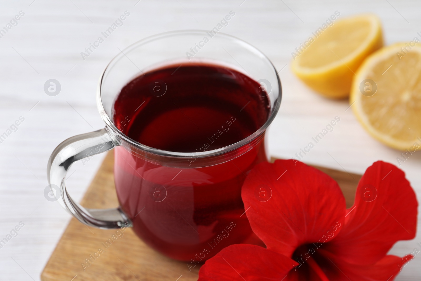 Photo of Delicious hibiscus tea and beautiful flower on white table, closeup