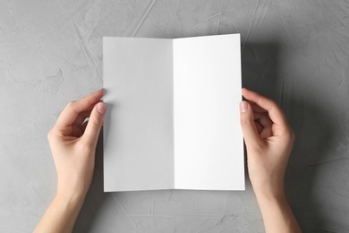 Photo of Woman holding blank brochure mock up on light background, top view