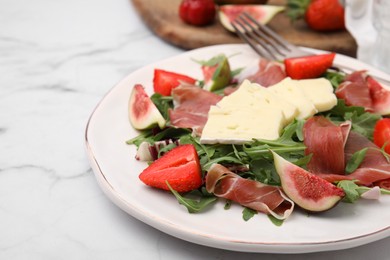 Tasty salad with brie cheese, prosciutto, strawberries and figs on white marble table, closeup. Space for text