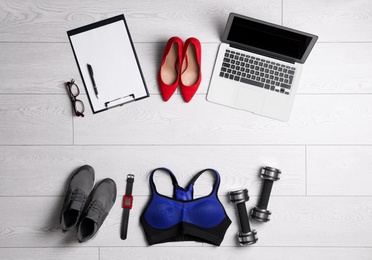 Photo of Flat lay composition with business supplies and sport equipment on white wooden floor. Concept of balance between work and life