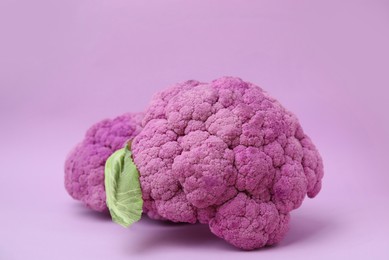 Photo of Whole fresh purple cauliflowers on violet background