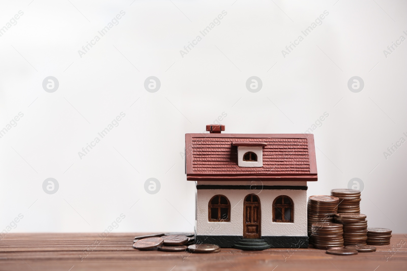 Photo of House model and coins on wooden table, space for text. Money savings