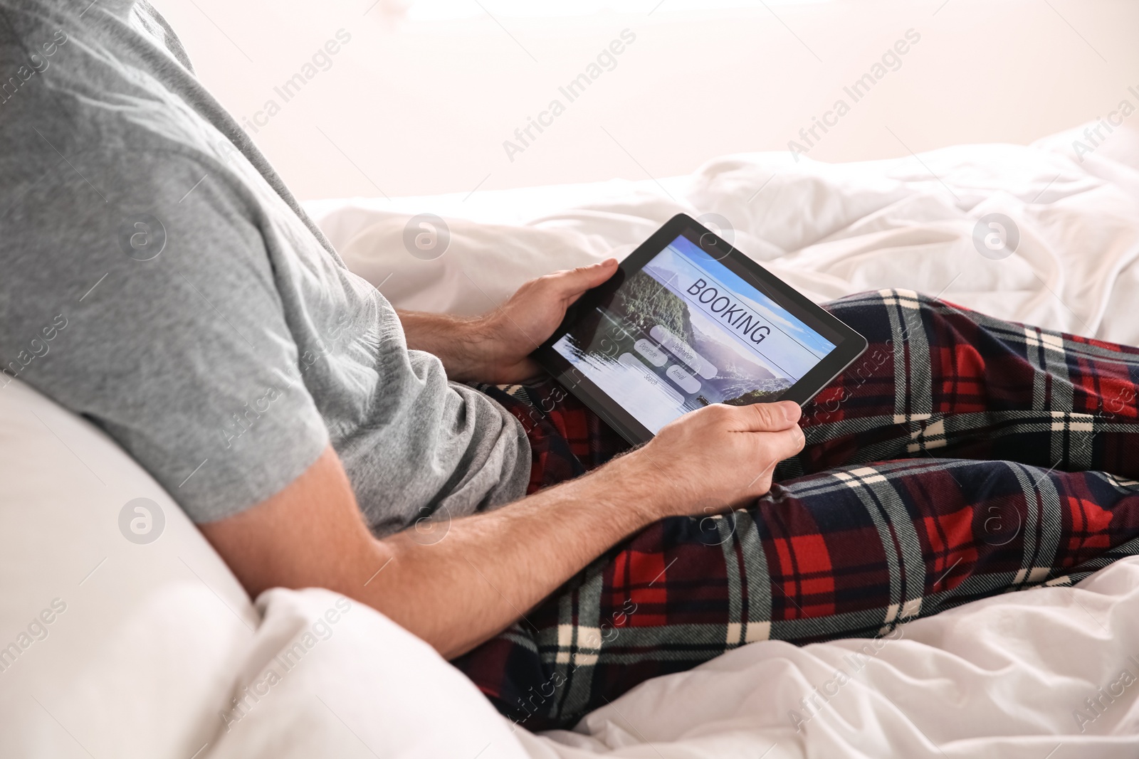 Photo of Man booking tickets online on bed, closeup. Travel agency concept