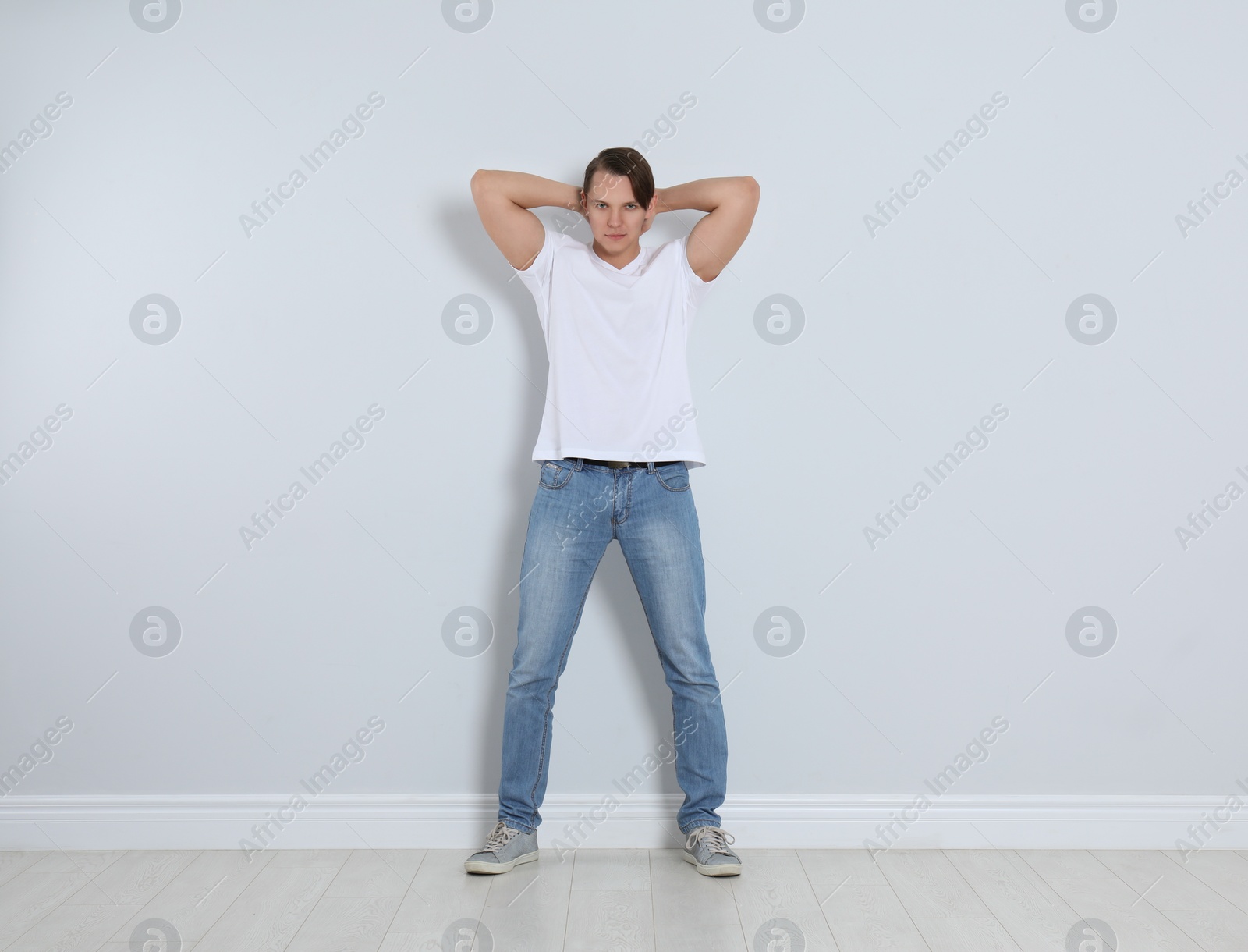 Photo of Young man in stylish jeans near light wall