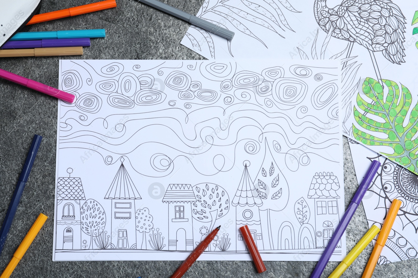 Photo of Antistress coloring pages and felt tip pens on grey table, flat lay