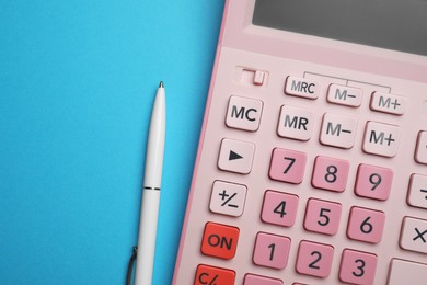 Calculator and pen on light blue background, flat lay