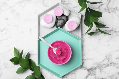 Flat lay composition with scrub, spa stones and candles on marble table