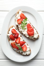 Photo of Delicious ricotta bruschettas with strawberry and arugula on white wooden table, top view