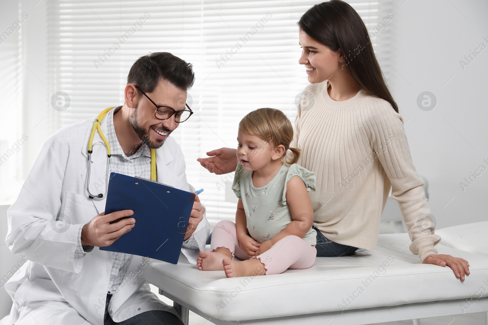 Photo of Mother and her cute baby having appointment with pediatrician in clinic. Doctor examining little girl