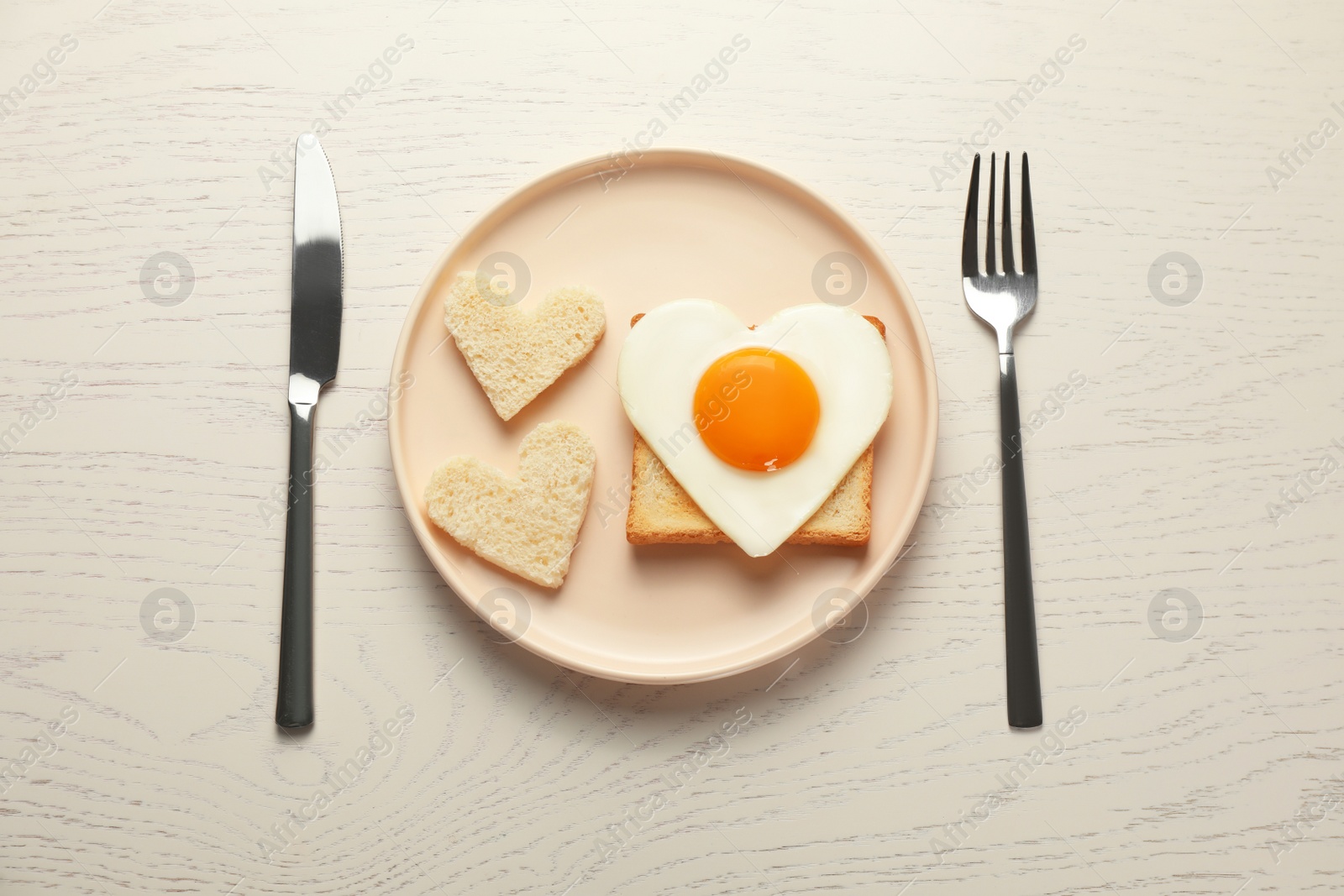 Photo of Heart shaped fried egg served on white wooden table, flat lay