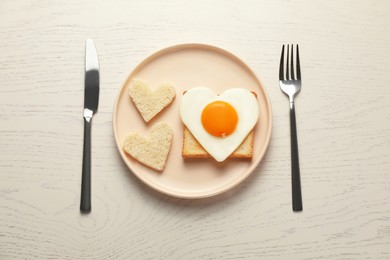 Photo of Heart shaped fried egg served on white wooden table, flat lay