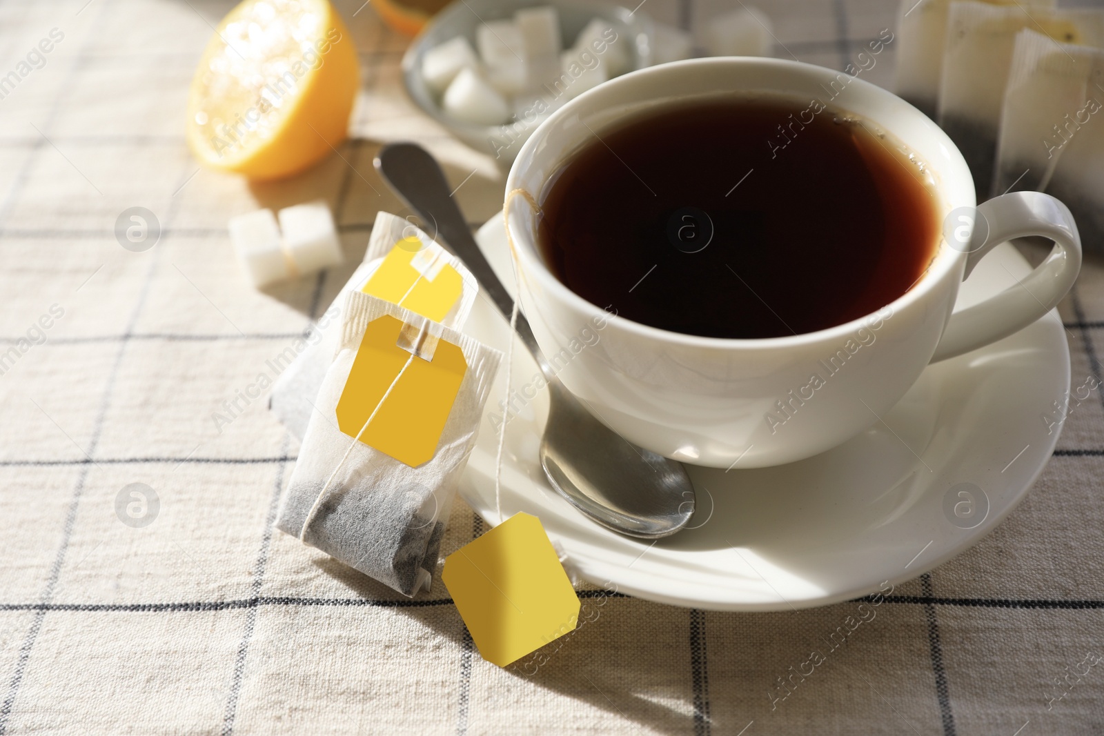 Photo of Tea bags near cup of hot drink on table, closeup