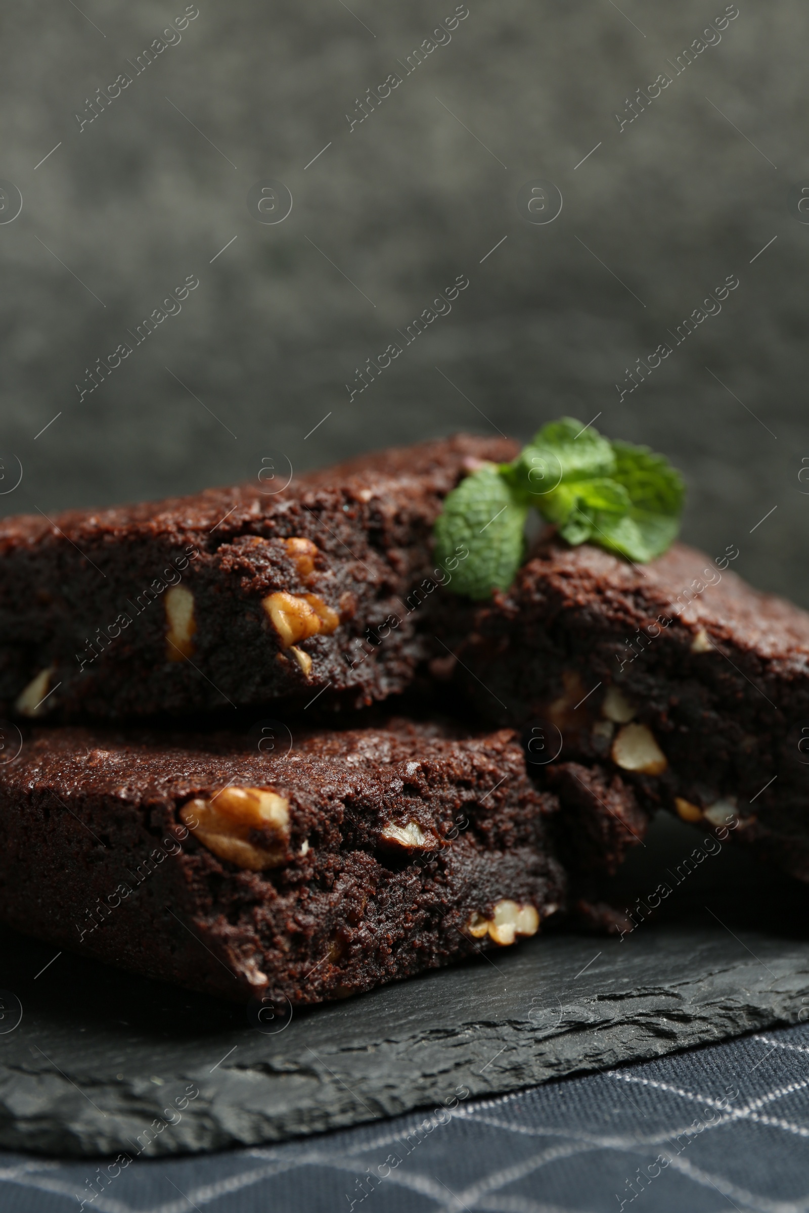 Photo of Delicious chocolate brownies with nuts and fresh mint on slate plate, closeup