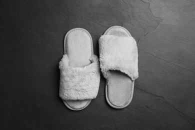 Photo of Pair of soft slippers on dark grey floor, top view