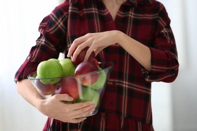 Photo of Woman holding bowl with ripe apples, closeup