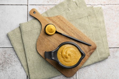 Tasty mustard sauce on light tiled table, top view