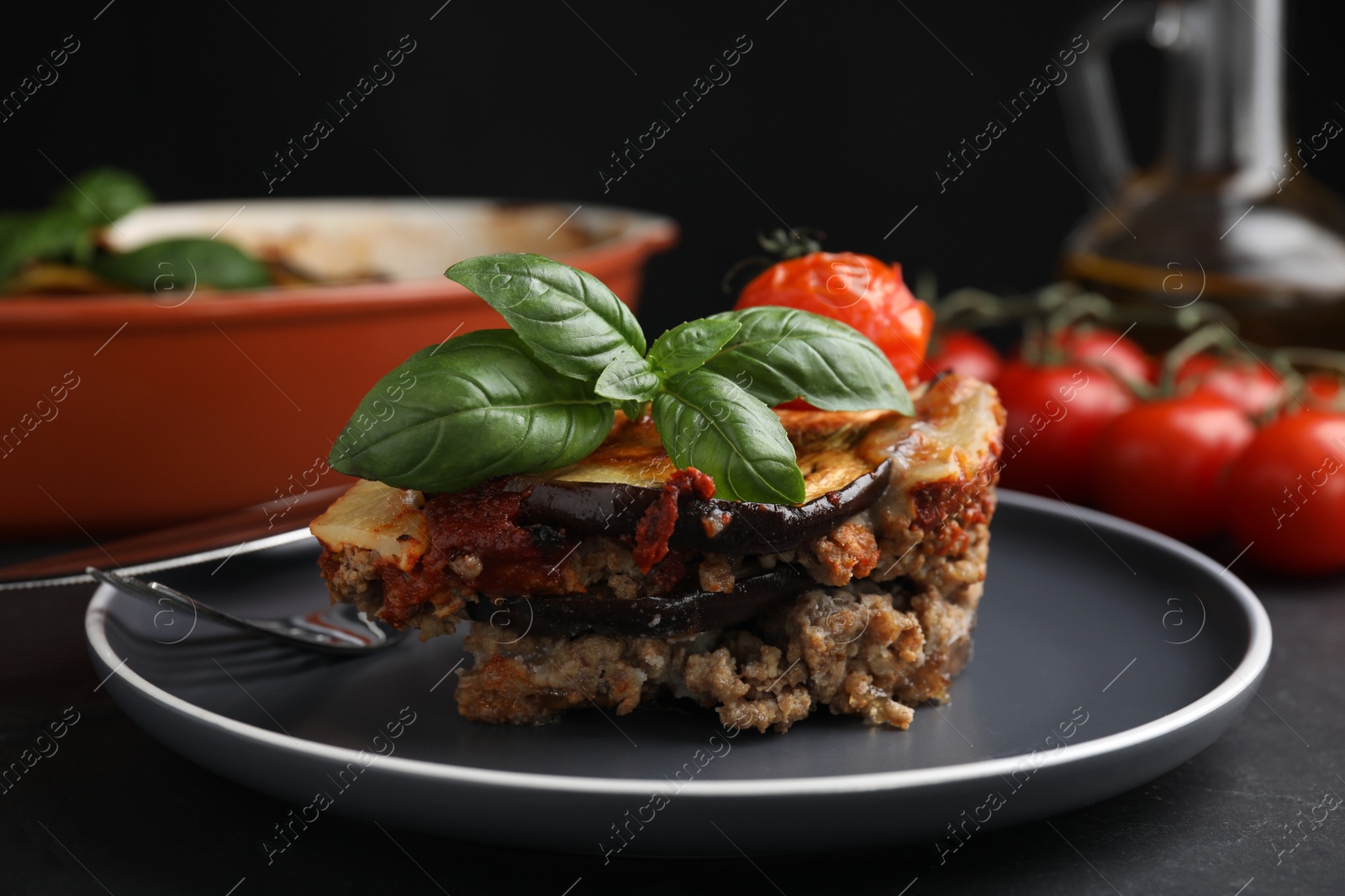 Photo of Plate of delicious eggplant lasagna served on black table, closeup