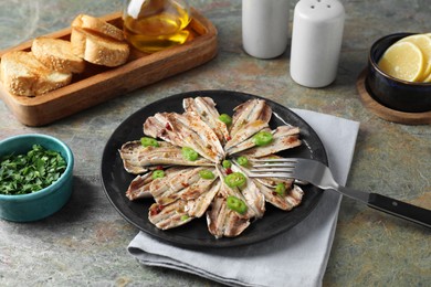 Photo of Tasty pickled anchovies served on textured table