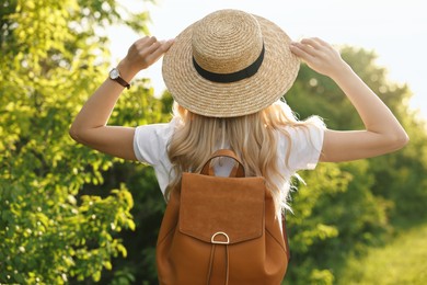 Young woman in straw hat outdoors on spring day, back view