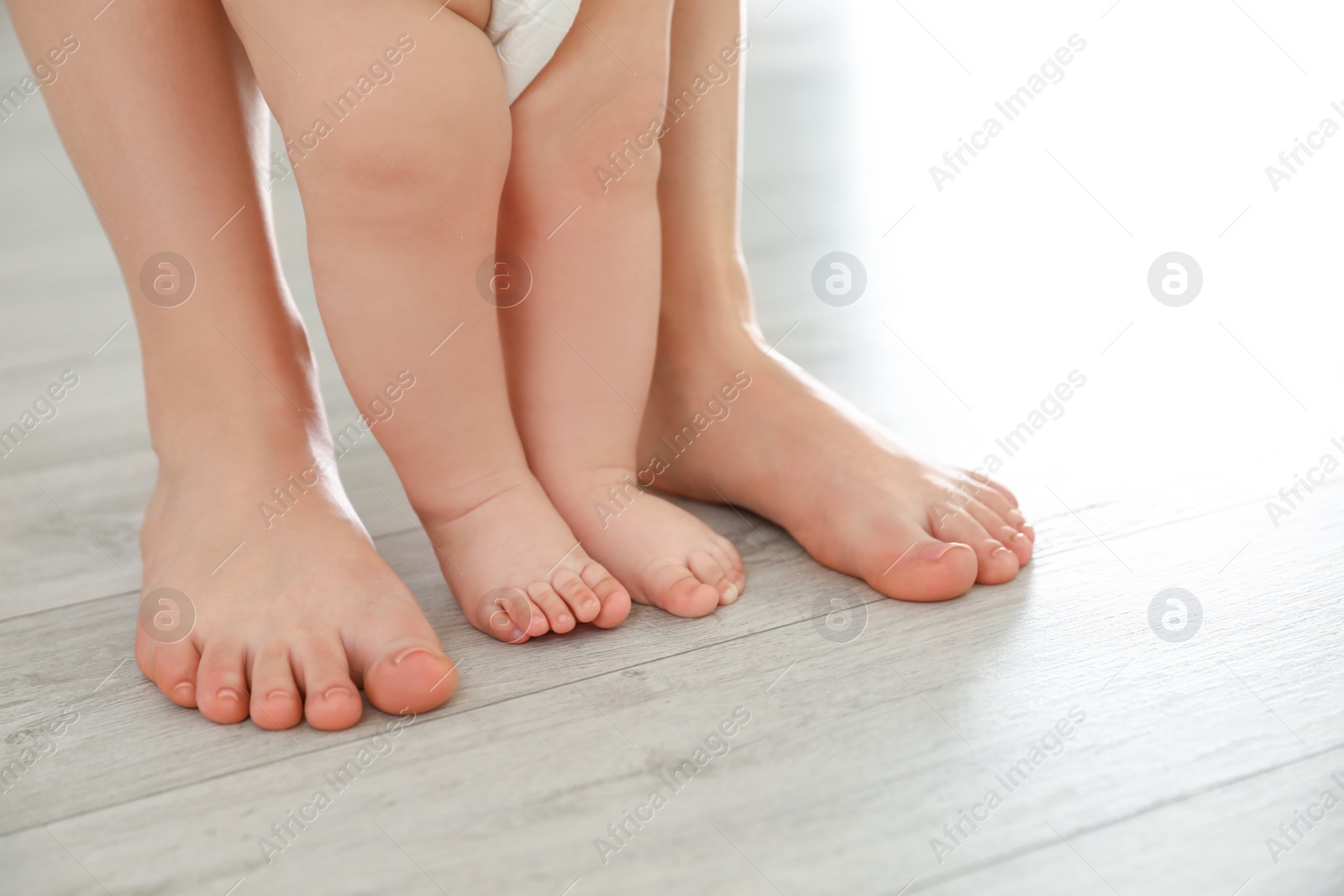 Photo of Mother and her baby standing on floor, closeup of legs