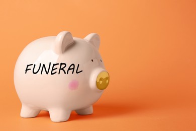 Image of Money for funeral expenses. Pink piggy bank on orange background, space for text