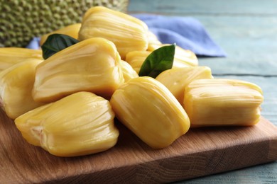 Photo of Fresh exotic jackfruit bulbs on light blue wooden table, closeup