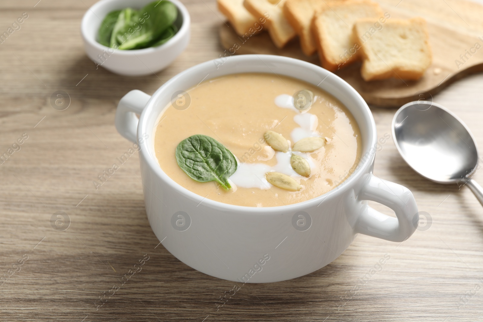 Photo of Healthy cream soup high in vegetable fats on wooden table, closeup