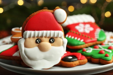 Photo of Tasty Christmas cookie in shape of Santa Claus on white plate, closeup. Space for text