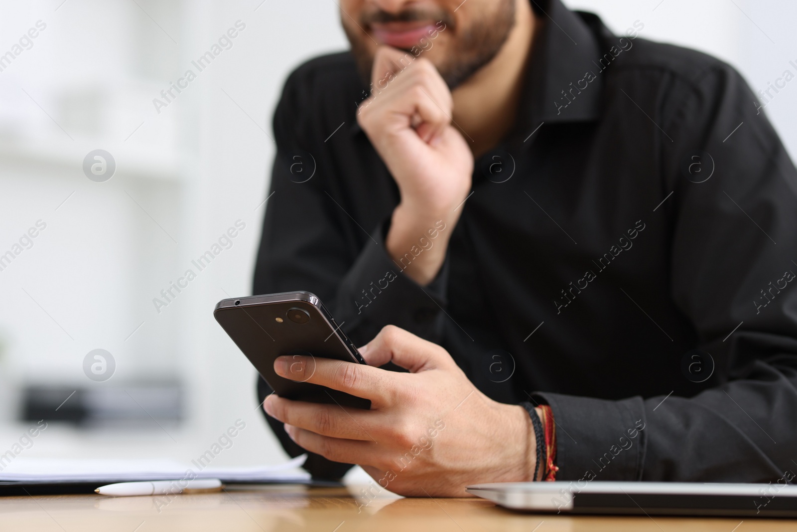 Photo of Man using smartphone at table in office, closeup