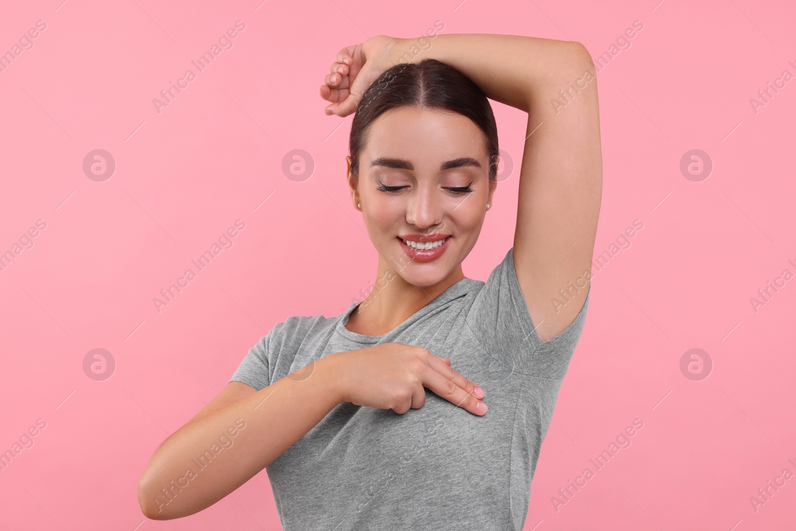 Photo of Beautiful young woman doing breast self-examination on pink background