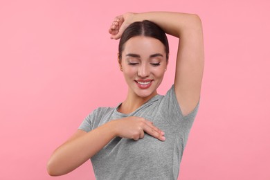 Photo of Beautiful young woman doing breast self-examination on pink background