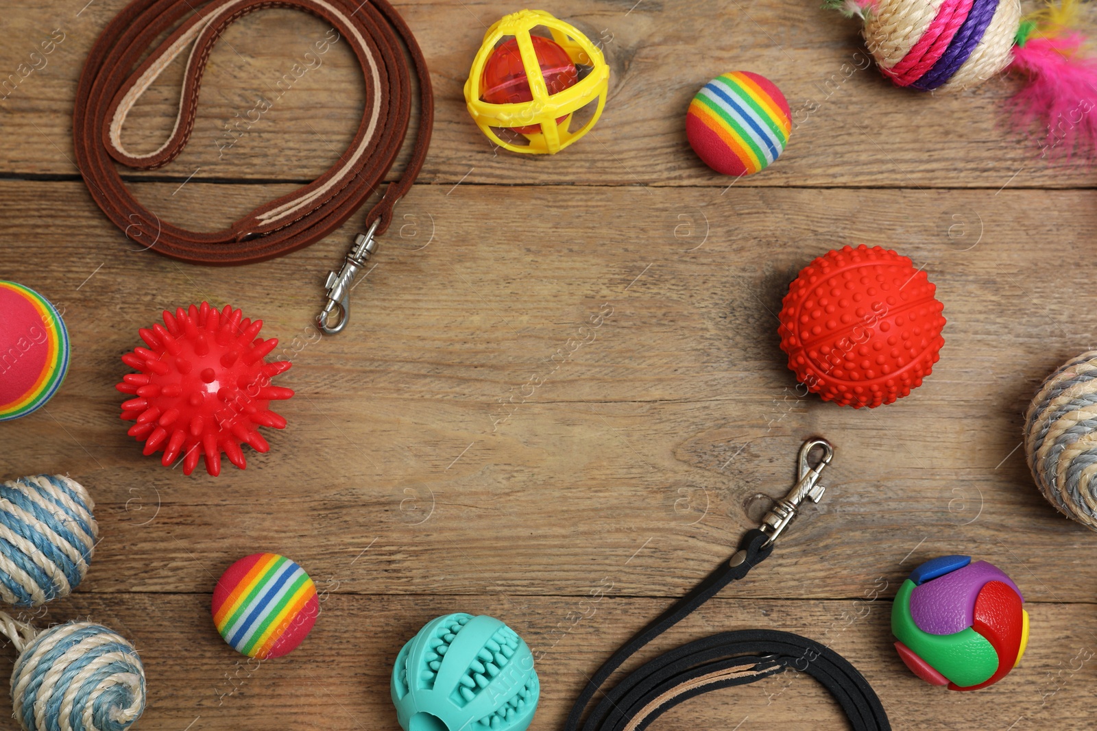 Photo of Flat lay composition with dog leashes and toys on wooden background, space for text