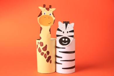 Toy giraffe and zebra made from toilet paper hubs on orange background. Children's handmade ideas