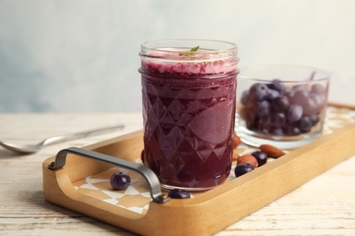 Photo of Tray with mason jar of delicious acai juice on table