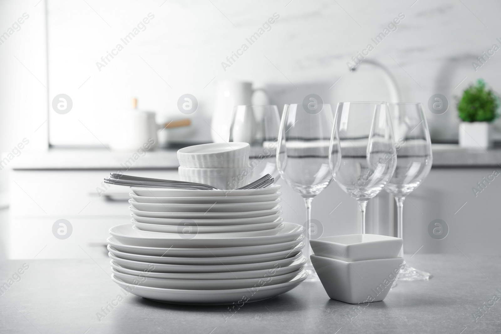 Photo of Set of clean dishes and cutlery on table in kitchen