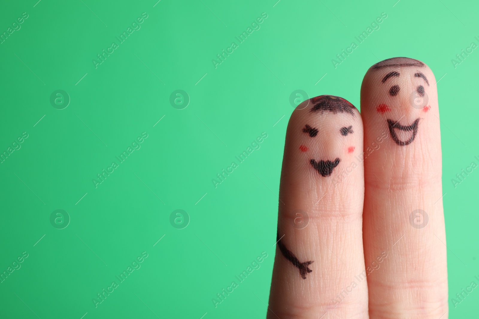 Photo of Two fingers with drawings of happy faces on green background, space for text. Spending time together