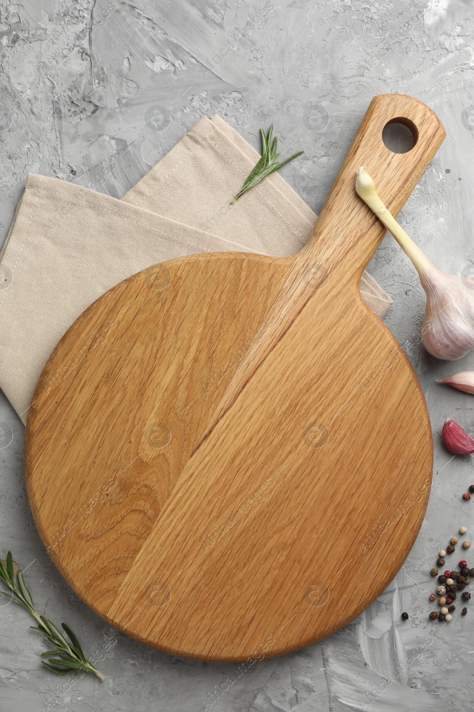 Photo of Cutting board, garlic, spices and rosemary on grey textured table, flat lay. Space for text