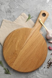 Photo of Cutting board, garlic, spices and rosemary on grey textured table, flat lay. Space for text