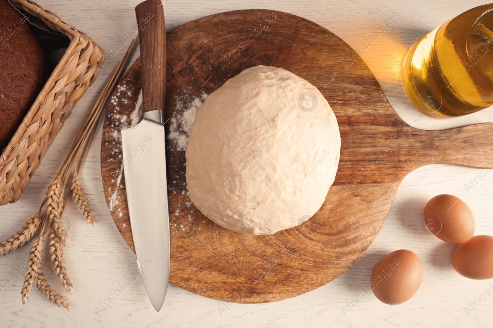 Photo of Fresh dough sprinkled with flour and other ingredients on white wooden table, flat lay