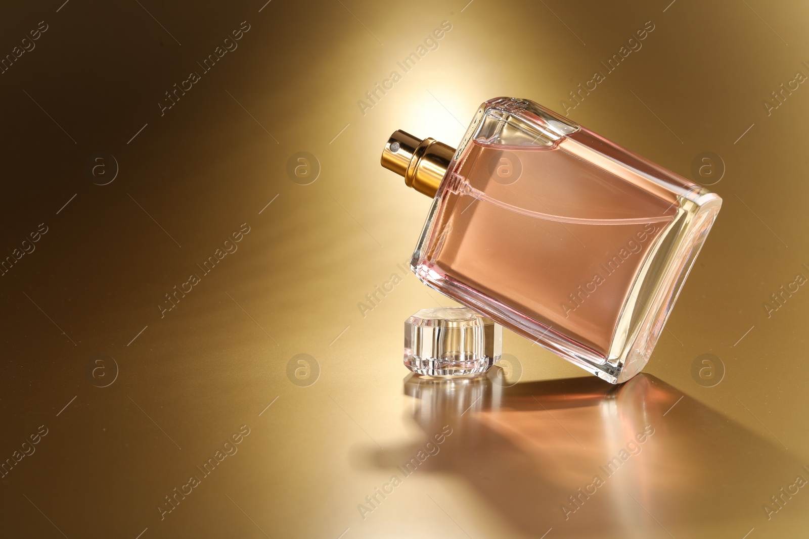 Photo of Luxury women's perfume. Sunlit glass bottle on golden background, space for text