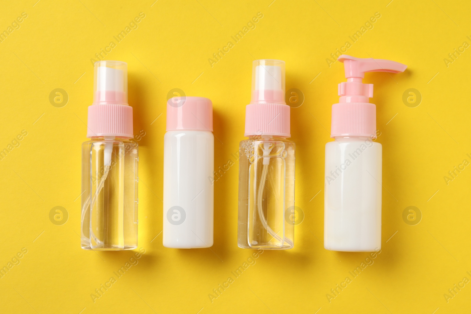 Photo of Cosmetic travel kit on yellow background, flat lay. Bath accessories