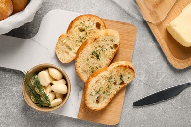 Photo of Tasty baguette with garlic and dill served on light grey table, flat lay