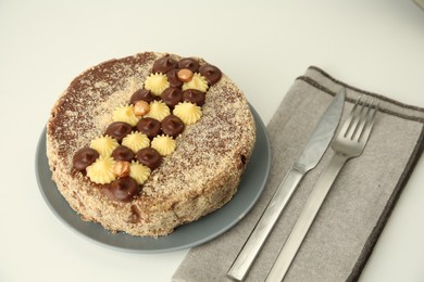 Photo of Delicious Kyiv Cake decorated with cream and hazelnuts on white table