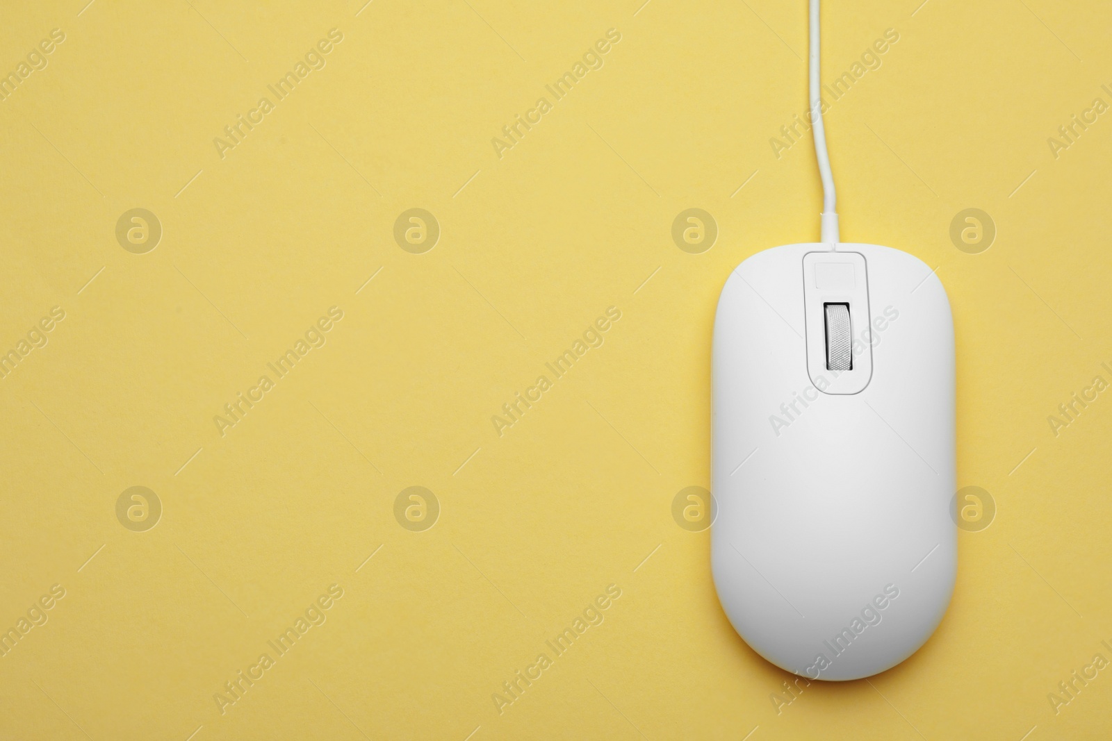 Photo of Wired computer mouse on yellow background, top view. Space for text