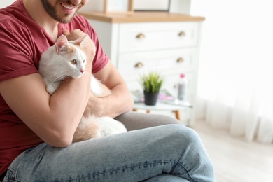 Young man with cute cat at home