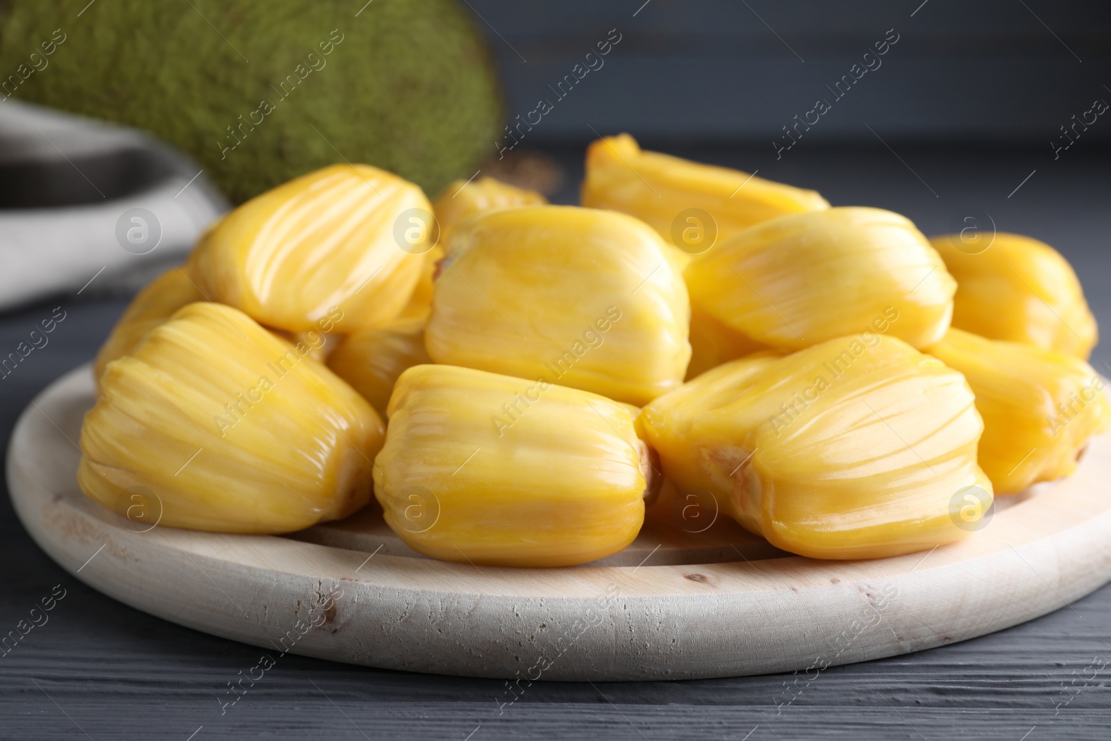 Photo of Fresh exotic jackfruit bulbs on grey wooden table, closeup