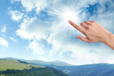 Image of Woman holding finger near bright light, closeup. Solar energy concept